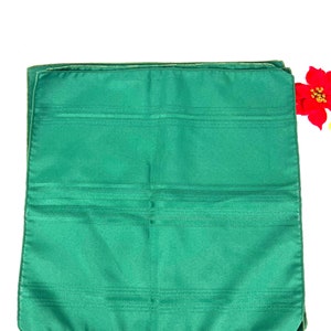 May include: A set of four green dinner napkins with a subtle striped pattern. The napkins are folded and stacked on a white background.
