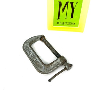 May include: A silver metal C-clamp with a handle and a screw. The clamp is marked "1420 21".