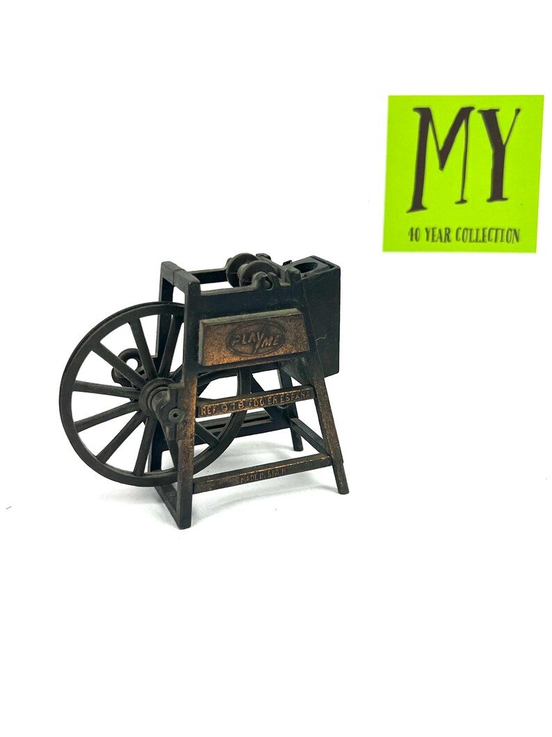 May include: A vintage metal pencil sharpener shaped like a spinning wheel. The sharpener is brown and has a small metal sign that reads "Playtime".