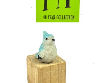 May include: A small blue and white bird figurine perched on a wooden block. The figurine is part of a 40 year collection.