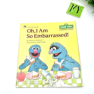 May include: A yellow Sesame Street children's book titled "Oh, I Am So Embarrassed!" featuring illustrations of Big Bird and Cookie Monster eating sandwiches. The book is part of the "Growing-Up Book" series.