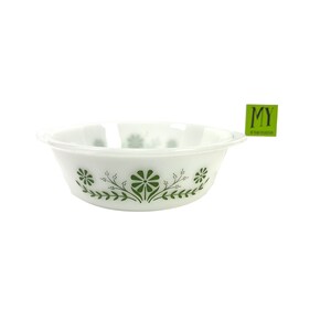 May include: White ceramic baking dish with a green floral design. The dish has a rounded shape and a handle on one side.