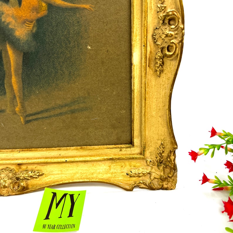 May include: A framed vintage print of a ballerina in a white tutu, with a gold ornate frame. The frame has a decorative design with a floral motif.