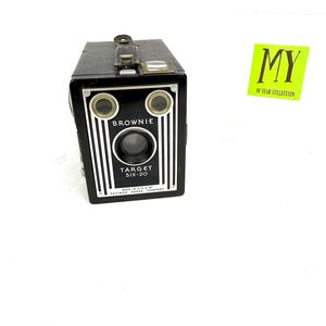 May include: Black Brownie Target Six-20 camera with white vertical stripes and the word "BROWNIE" above the lens. The camera has a handle and the text "MADE IN U.S.A. BY EASTMAN KODAK COMPANY". A green sticker reads "MY 40 YEAR COLLECTION".