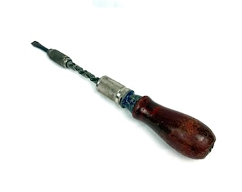 May include: A vintage hand drill with a dark wooden handle and a metal chuck. The drill bit is visible, and the tool appears to be well-used. A green sticker with the text "MY 40 YEAR COLLECTION" is in the background.