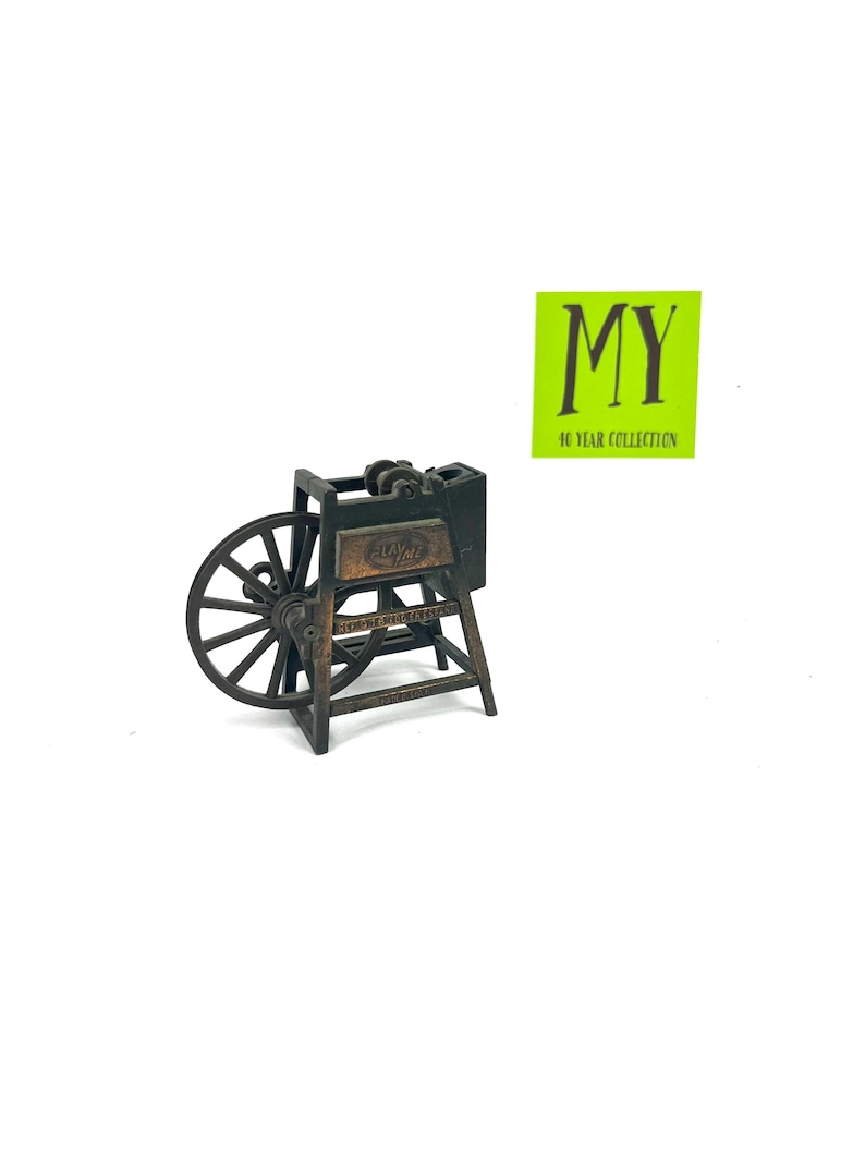 May include: A vintage-style metal pencil sharpener shaped like a small wooden wheel with a crank. The sharpener is brown and black and has the word "Playtime" on the side.