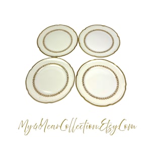 May include: Set of four white ceramic plates with a gold leaf design around the rim.