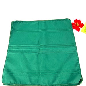 May include: A stack of four green dinner napkins with a subtle striped pattern. The napkins are folded in half and have a smooth, silky texture.