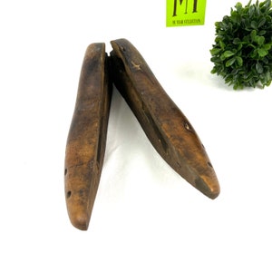 May include: A pair of antique wooden shoe stretchers, also known as shoe trees, with a light brown finish. The stretchers are open and have a slightly curved shape.
