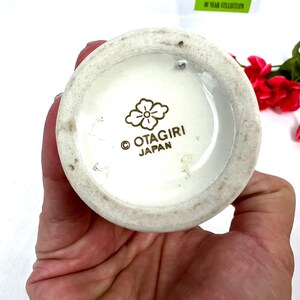 May include: White ceramic vase with a gold floral design and the words "Otagiri Japan" on the bottom.