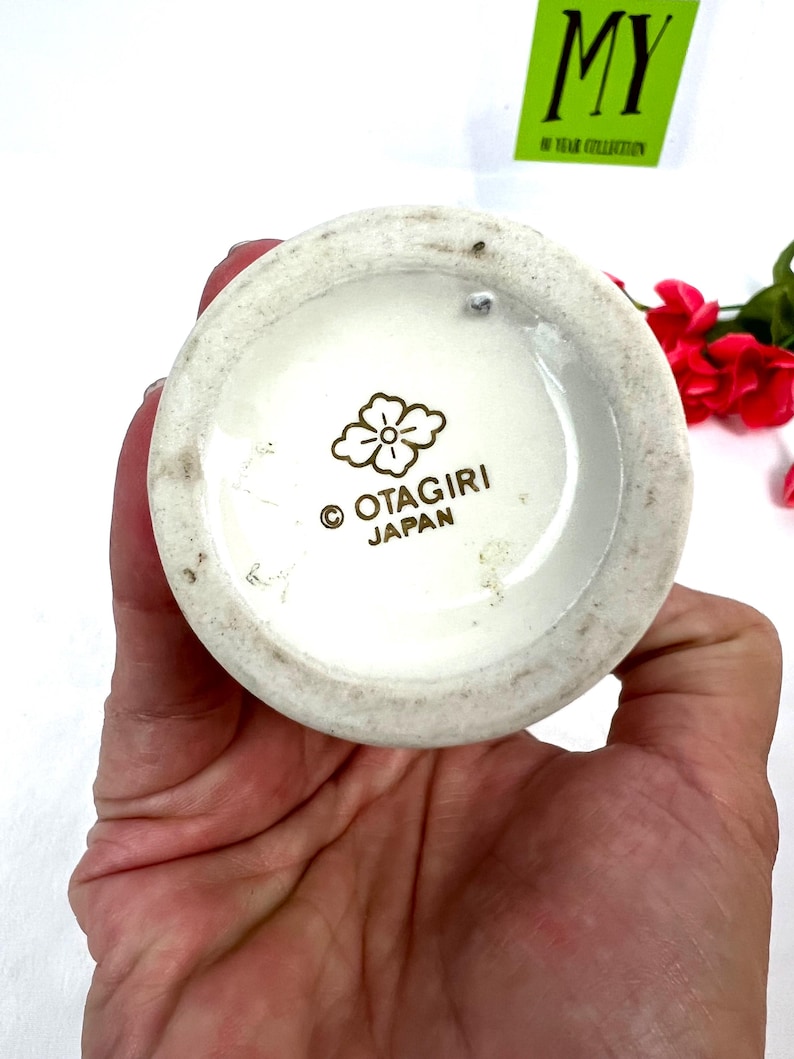 May include: White ceramic vase with a gold floral design and the words "Otagiri Japan" on the bottom.