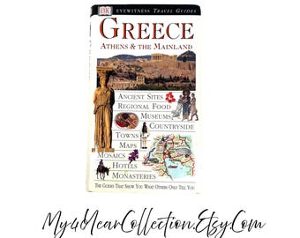 May include: A travel guide titled "Greece Athens & The Mainland" with a photo of ancient ruins. The cover includes text about ancient sites, regional food, museums, towns, maps, mosaics, hotels, and monasteries. The guide is from the "DK Eyewitness Travel Guides" series.