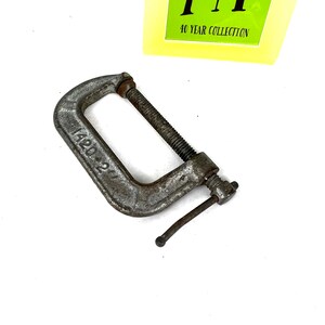 May include: A silver metal C-clamp with a handle and a screw. The clamp is labeled "42D".