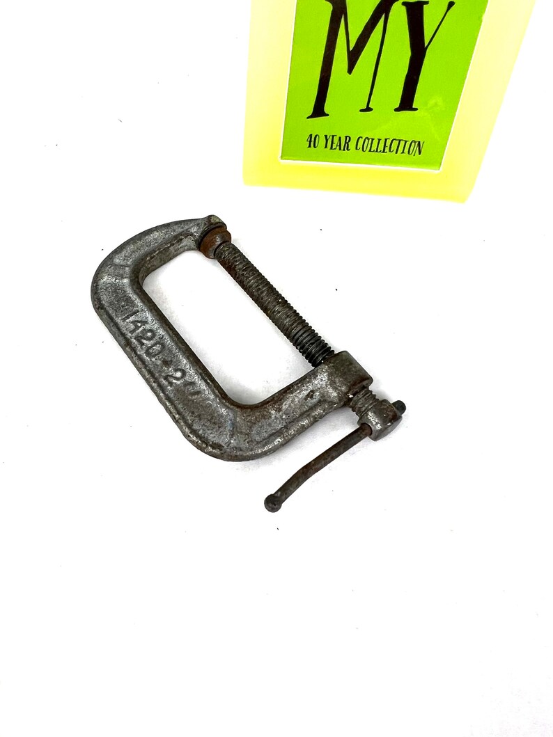 May include: A silver metal C-clamp with a handle and a screw. The clamp is labeled "42D".