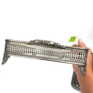 May include: Silver plated serving tray with an ornate design and four feet. The tray has a decorative, openwork design.
