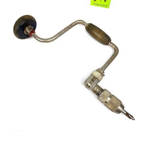 May include: An antique hand drill with a wooden handle and a metal frame. The drill bit is visible at the end. The tool has a dark wooden knob and a red accent. The label in the image reads "MY 40 YEAR COLLECTION".