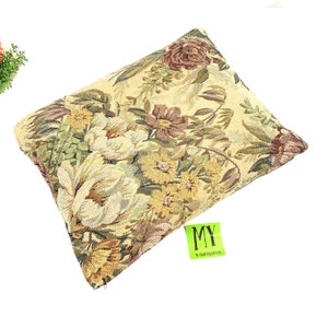 May include: A rectangular pillow with a floral tapestry design in shades of green, brown, and yellow. The pillow has a zipper closure and a tag that reads "MY 70 YEAR COLLECTION".