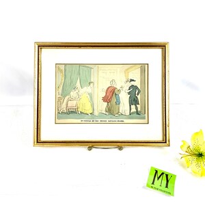 Peut inclure: Une estampe ancienne encadrée représentant une scène humoristique d'un groupe de personnes dans une porte. L'estampe est intitulée "Do's Mistake in the Wrong Lodging House."