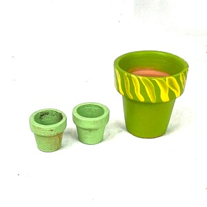 May include: Three green terracotta pots, one with a yellow and brown striped design. The pots are all different sizes.