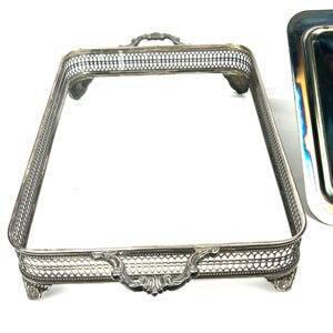 May include: Silver serving tray with a decorative, openwork design and ornate handles. The tray has four feet and is rectangular in shape.
