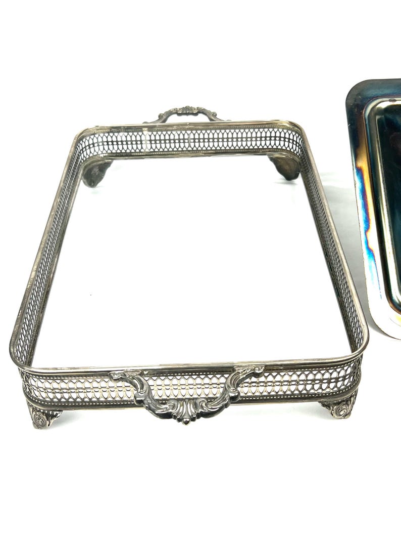 May include: Silver serving tray with a decorative, openwork design and ornate handles. The tray has four feet and is rectangular in shape.