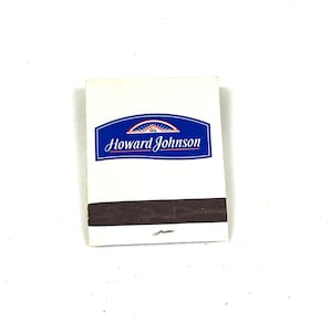 May include: A white matchbook with a blue and white logo that says "Howard Johnson" in a cursive font. The matchbook has a brown strike surface.