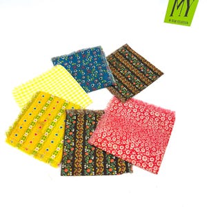 May include: A selection of small, square fabric patches with frayed edges. The patches display diverse floral and patterned designs in colours such as yellow, blue, red, and brown. A green label with the text "MY 50 YEAR COLLECTION" is in the upper right corner.
