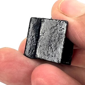 May include: A small, black, rectangular block of licorice candy.