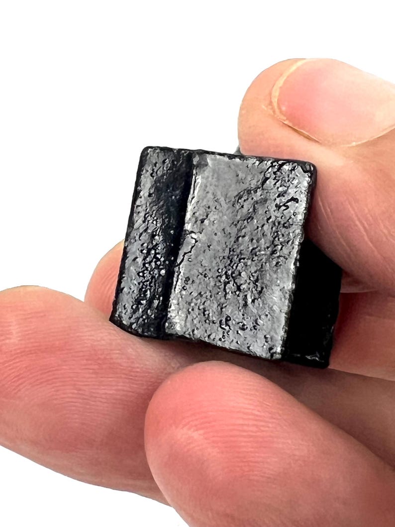 May include: A small, black, rectangular block of licorice candy.