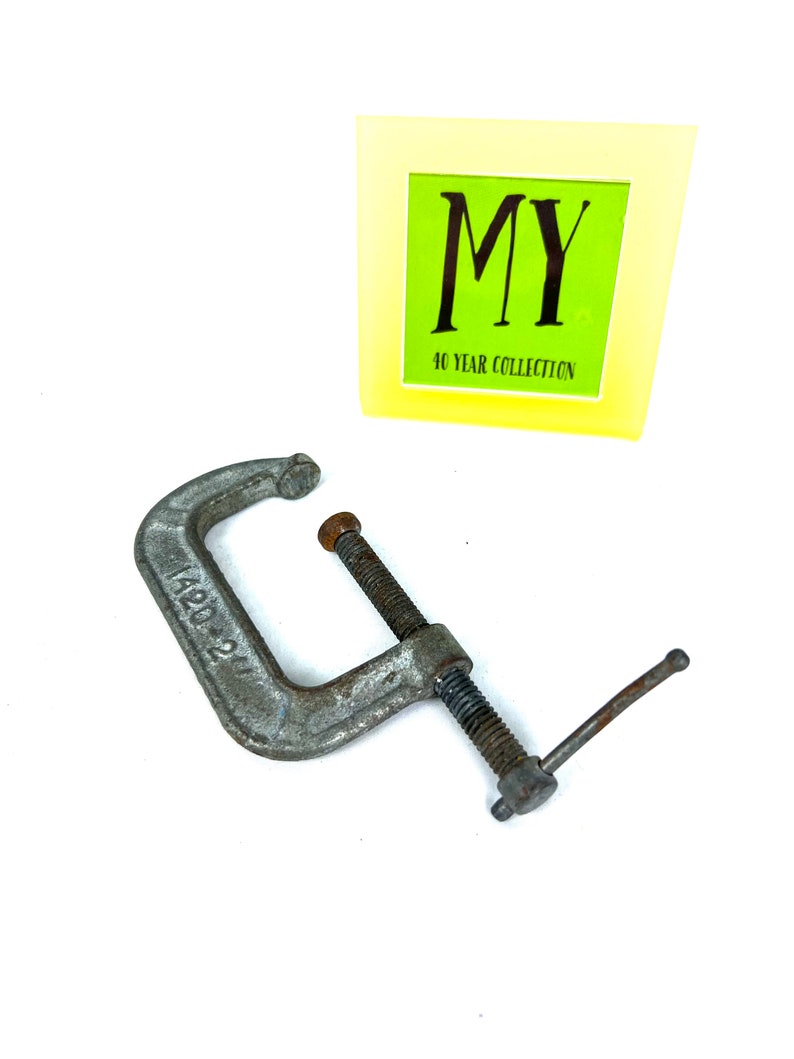 May include: A silver metal C-clamp with a threaded screw and a handle. The clamp is marked with the number "1420-21".