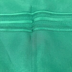 May include: A teal fabric with a striped pattern. The fabric has a subtle sheen and a smooth texture.