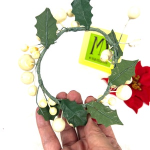 May include: White faux berry and green leaf candle ring. The ring is made of wire and has a diameter of approximately 4 inches.