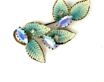 Peut inclure: Broche vintage en forme de brindille de feuilles. Les feuilles sont turquoise pâle avec une bordure dorée et de petits cristaux transparents. La broche a un fermoir doré.
