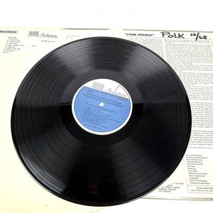 Puede incluir: Un disco de vinilo negro de "Theatre Productions" con "The Musical Version of Tom Jones". La etiqueta del disco es azul y blanca. La portada del &aacute;lbum y las notas del forro son visibles en el fondo. El texto "MY 40 YEAR COLLECTION" es visible.