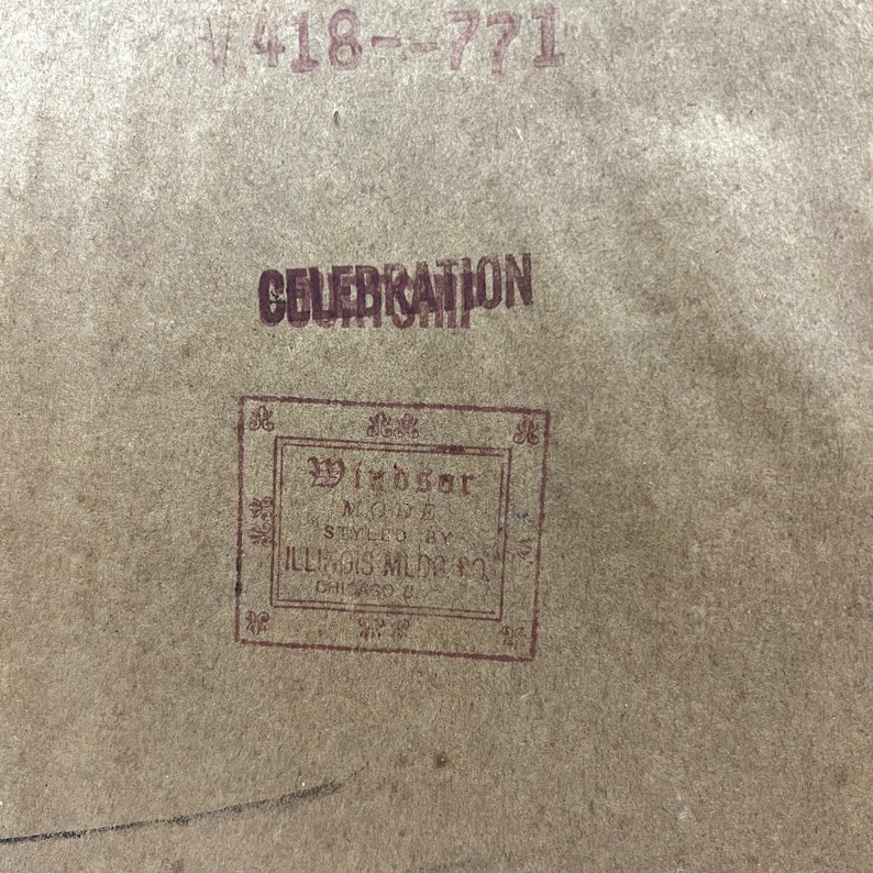 May include: A close-up of a brown paper tag with the text "CELEBRATION" and "Windsor Model Styled by Illinois Mfg. Co. Chicago, Ill."