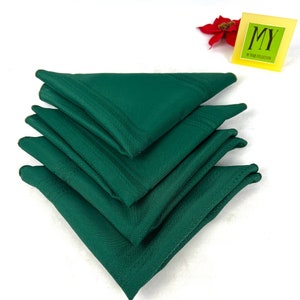 May include: A stack of four dark green linen napkins. The napkins are folded in a triangular shape.