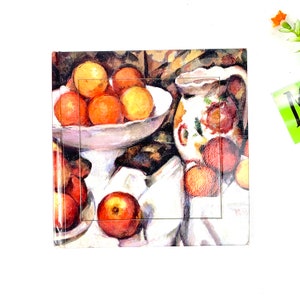 May include: A still life painting of a white ceramic bowl filled with oranges and a white pitcher with a floral design. The bowl is on a white cloth with apples and oranges around it. The background is a dark brown with a textured surface.