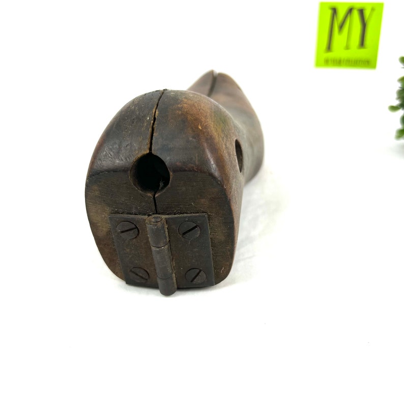 May include: A vintage wooden shoe last with a hinged design. The last is made of dark brown wood and has a smooth, worn finish. The hinge is made of metal and has four screws.