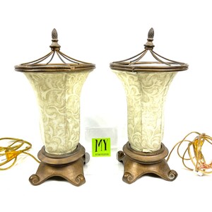 May include: Two gold table lamps with white fabric shades featuring a floral pattern. The lamps have a cage-like design around the top of the shade and a finial on top.