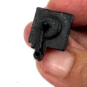 May include: Black plastic toy telephone with a rotary dial and a cord. The phone is in a hand.