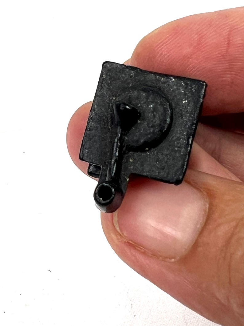 May include: Black plastic toy telephone with a rotary dial and a cord. The phone is in a hand.