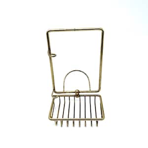 May include: Gold metal soap dish with a raised bar for holding a bar of soap. The dish has a decorative design and is perfect for a bathroom.