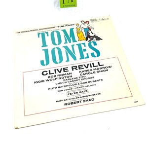 Puede incluir: Una portada de &aacute;lbum de vinilo vintage para "Tom Jones", con un t&iacute;tulo turquesa y los nombres del elenco. La portada incluye ilustraciones de personajes con vestuario de &eacute;poca. El &aacute;lbum es una grabaci&oacute;n musical.