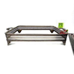 May include: A silver serving tray with a decorative, woven design and four feet. The tray has a rectangular shape and is made of metal.