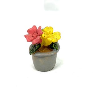 May include: A miniature gray flower pot with two flowers, one red and one yellow, and green leaves. The flowers are in full bloom and the pot has a textured surface. The pot is a miniature decorative item.