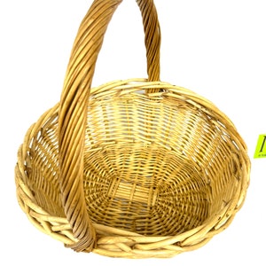 May include: A natural woven wicker basket with a single handle. The basket is oval shaped and has a light brown color.
