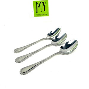 May include: Three stainless steel spoons with a beaded edge design. The spoons are arranged diagonally against a white background. The text "MY 40 YEAR COLLECTION" is in a green rectangle in the upper left corner.