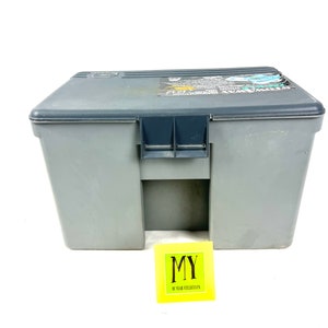 May include: A gray plastic storage box with a black latch and a label on the top that reads "Plano Tackle Box".