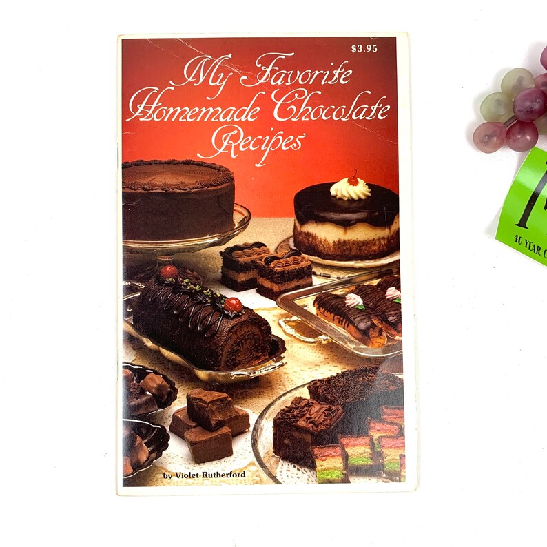 May include: A cookbook titled "My Favorite Homemade Chocolate Recipes" by Violet Rutherford. The cover features a variety of chocolate desserts, including cakes, pastries, and truffles.