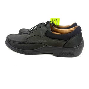 May include: Black leather shoes with laces. The shoes have a rounded toe and a thick sole. The words "Formula Antistatica" are printed on the side of the sole. The shoes are designed for comfort and durability.